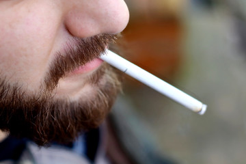 Portrait of brutal adult working  man after labor day  with a beard close up smoking  cigarette,...