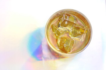 Glass with whiskey and ice cubes on multicolored rainbow background. Part of set.