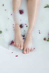 photoshoot with flowers and a milk bath, foot in the water with flowers, feet close up