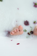 Fototapeta premium foot in the water with flowers, milk; feet close up, feet in the bathroom