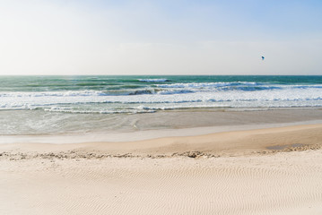 Sandy seashore with clear water and huge waves in the sea.