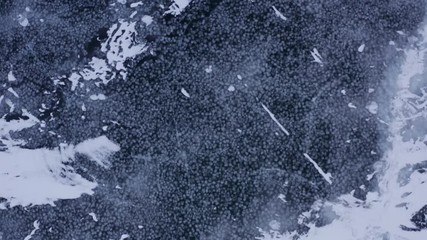 Winter frozen lake aerial moving forward looking down over ice and fishing shacks - Powered by Adobe