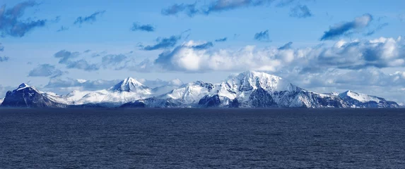 Gordijnen Gletsjer Snow peaks, glaciers and rocks of Aleutian islands in sunny winter day as viewed from ship passing in calm sea  © Oleksii Fadieiev