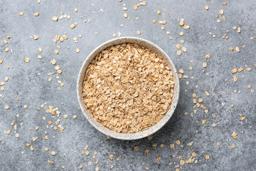 Rolled oats or oat flakes in bowl, table top view. Concept of healthy eating, dieting, vegan or vegetarian diet