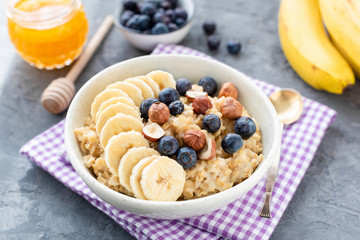 Oatmeal porridge with fruits banana, blueberries and hazelnuts. Healthy eating, dieting, weight loss concept
