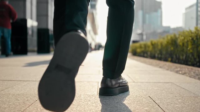 Close Up Unrecognizable Business Man Legs in Suit and Shoes Walking Outdoors in the Center of Big City with Blurred Pedestrians in Busy Street in Spring Sunny Day. Low Angle 4K Slow Motion Video Shot