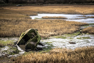 A lonely decaying row boat submerged in water at a nature reserve on the Kent coast.