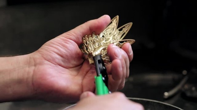 the jeweler makes a pendant of gold. Craft jewelery making with professional tools. Jeweler working in workshop