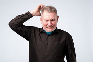 Portrait of casual mature man in black shirt thinking and looking puzzled.