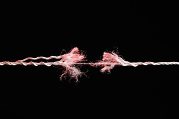 Tearing the red rope in the middle of the frame on black background