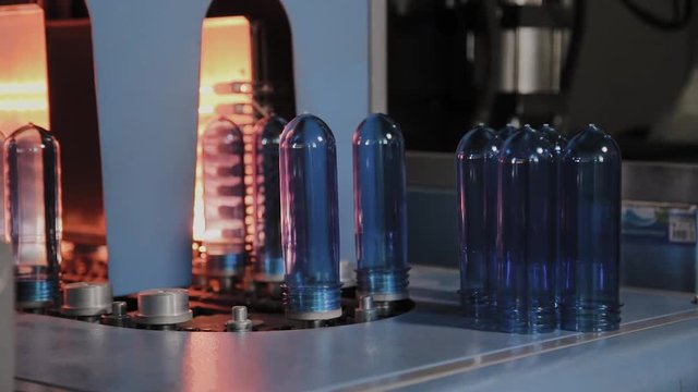 PET preforms move on heating oven line in fast speed. Plastic bottles production