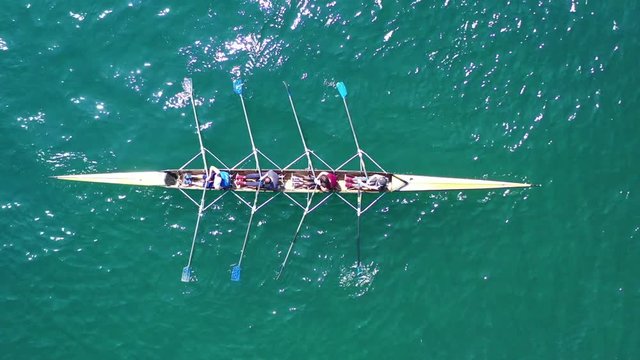 Aerial drone bird's eye view video of yellow sport canoe operated by team of young team in emerald clear sea