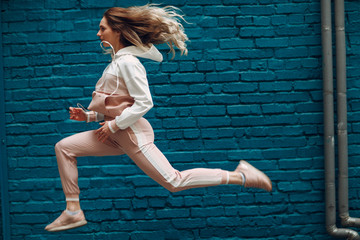 Athletic young woman in a pink sports suit. Jump and running female.