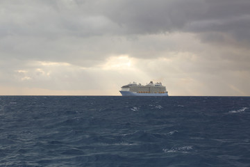 Fototapeta na wymiar Cloudy skies and cruise ship on turbulent water