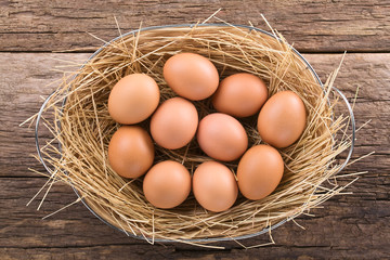 Fresh raw brown eggs on hay in basket, photographed overhead (Selective Focus, Focus on the top of the eggs)