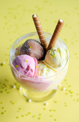 A cup of ice cream with rolled wafers. ice cream closeup, with yellow background.