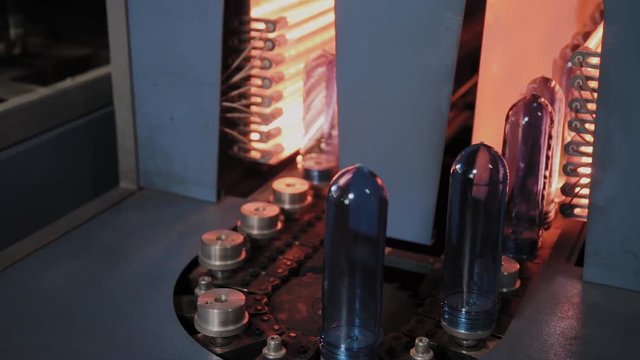 PET preforms move on heating oven line in fast speed. Plastic bottles production