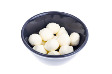 Small white mozzarella balls in black bowl.