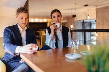 A stylish couple drinks morning coffee at the cafe, young businessmen and freelancers