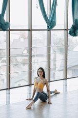 Fototapeta na wymiar young attractive girl doing fitness exercises with yoga on the floor against the background of panoramic windows