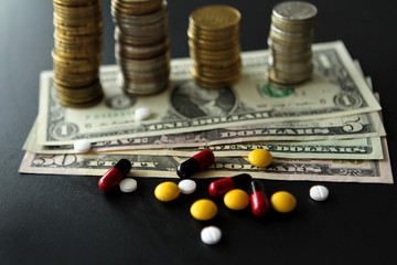 Pills and capsules and dollar banknotes, stacks of coins in the background. The concept of costly treatment, health close-up