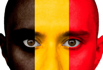 National flag Belgium colored depicted in paint on a man's face close-up, isolated on a white background