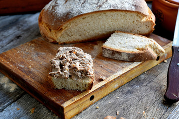 Homemade rustic bread and chicken pate on a wooden background.