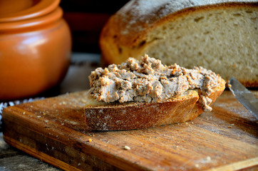Homemade rustic bread and chicken pate on a wooden background.