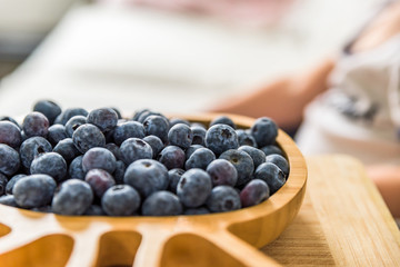 wooden bamboo plate full of fresh blueberries with baby boy on background