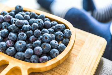wooden bamboo plate full of fresh blueberries with baby boy on background