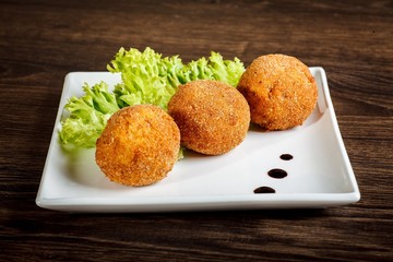Croquettes or falafel ans salad on a white plate on a dark wooden table background. Middle eastern or arabic dishes. Halal food for ramadan
