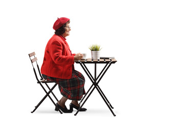 Elderly woman drinking coffee at a table alone