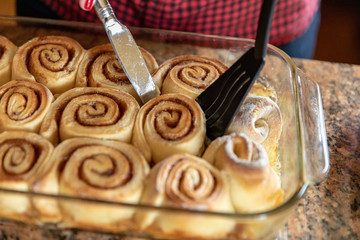 Knife & Spatula Lifting a Homemade Cinnamon Roll From a Baking Dish