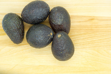 bunch of ripe avocados on a light wooden table