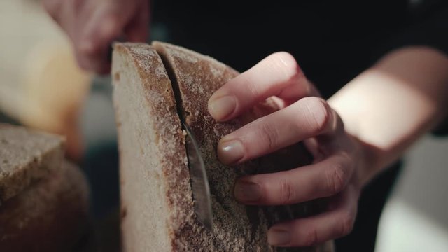 Female chef cutting slice from a whole wheat bread 4k 