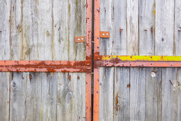 Old gray gate on large rusty hinges