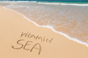 Inscription VITAMIN SEA on sandy beach