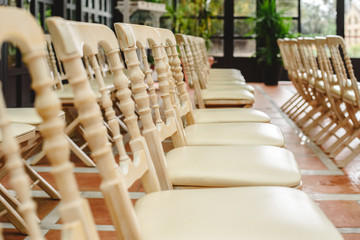 Many empty white wooden chairs lined up for a retro style event.