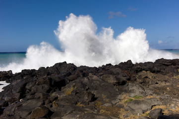 wave splashing on black lava rocks with blue sky in the big Island of Hawaii