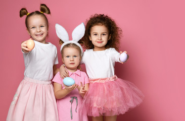 Three smiling dressed up for the holiday kid girls demonstrate painted eggs on Easter day