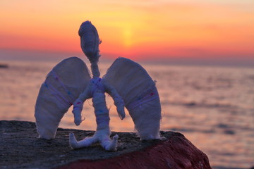 an angel sits on the beach at sunrise