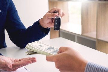Rental agreement for signing a car insurance policy Document and Form of a Vehicle Sales Agreement, the agent is holding the document and car key.