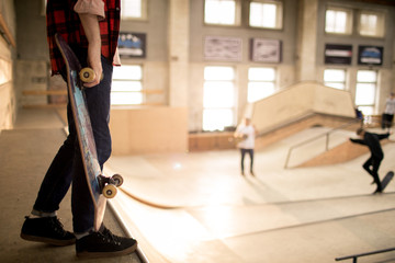 Legs of unrecognizable skater standing on ramp ready to do stunts in extreme park, copy space