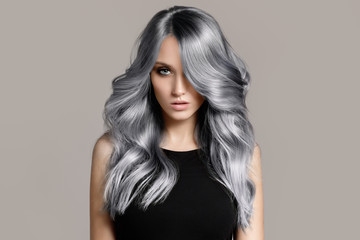 Beautiful woman with long wavy coloring hair. Flat gray background. - 260166914