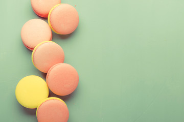 Pink yellow macaroons cake on pastel green background, neon color, place for text, creative layout, top view