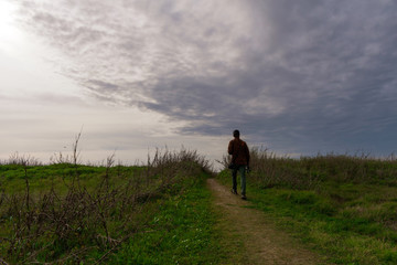 Nature Photographer In Action Walking  Down A Grassy Trail  Dressed in Trendy Clothing