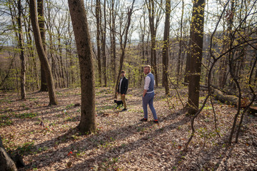 Obraz premium two men, young gay couple walking in forest with their dog.