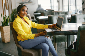 Elegant black woman. Lady in a yellow jacket. Businesswoman working in a office