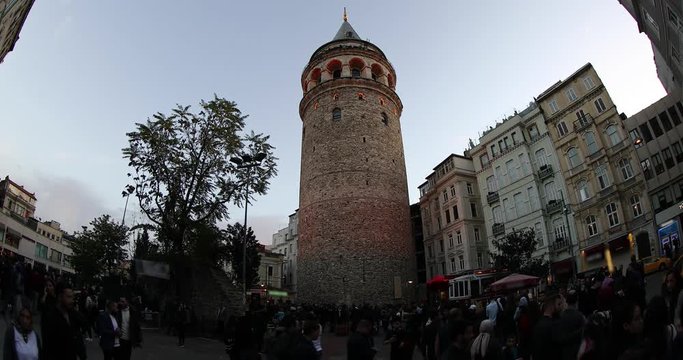 Galata tower is medieval stone tower in Karakoy squere Istanbul Turkey. Tourists visiting Galata Tower at evening. Time Lapse