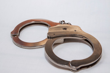 A single set of silver, metal handcuffs on a white background